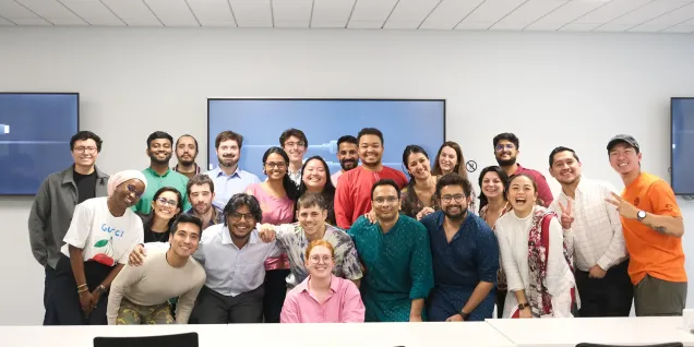 Photo de groupe lors d’un événement d’entreprise, avec une équipe réunie dans une salle de réunion moderne, devant deux écrans muraux.