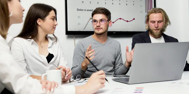 Réunion d’équipe autour d’un ordinateur avec présentation de données et graphiques lors d’un atelier de travail collaboratif.