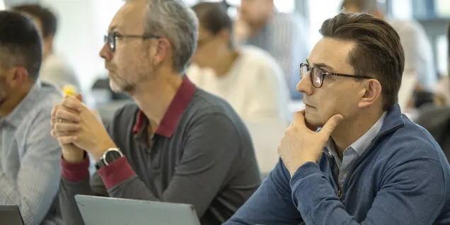 Personnes assises et concentrées, utilisant des ordinateurs portables lors d’une session de formation ou de certification en salle.