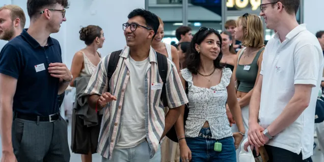 Group of people wearing name badges walking and conversing inside the emlyon campus in Lyon during a student event.