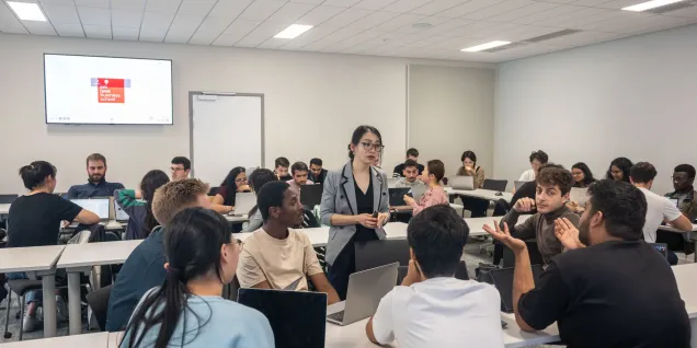 Group discussion taking place in emlyon classroom with students working on laptops