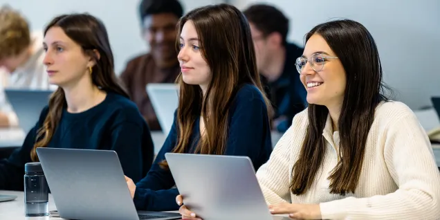 Étudiants assis à des tables utilisant des ordinateurs portables pendant un cours dans une salle de classe d’emlyon.