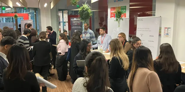 WiDS event at emlyon Paris campus: attendees networking around partner booths during an indoor session, February.