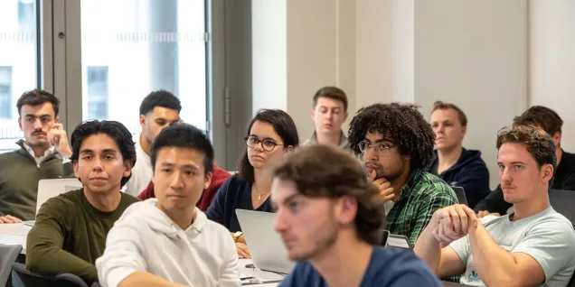 Group of students listening to a lecture with laptops in a business school classroom