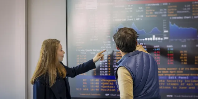 Professionnels examinant des graphiques et analyses financières sur un écran numérique dans un contexte d’enseignement ou d’analyse business
