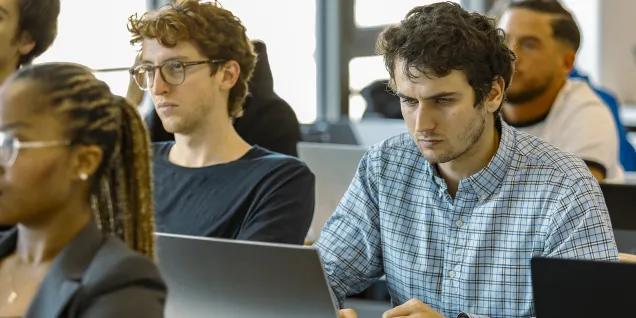 Students working on laptops during a finance class in a classroom at emlyon business school.