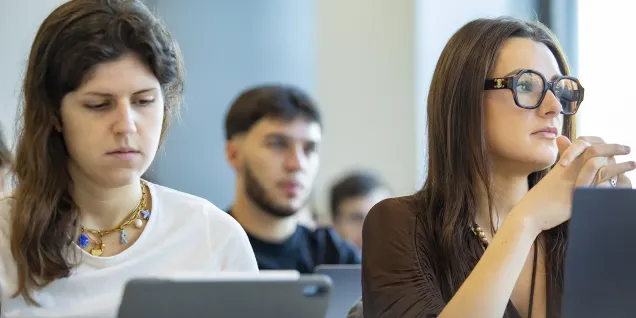 Étudiant en salle de cours échangeant avec d’autres participants lors d’une formation en école de commerce.
