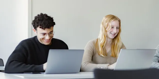 Étudiants utilisant des ordinateurs portables pendant une séance de formation dans une salle de classe moderne.