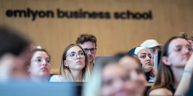 Participants assis dans un amphithéâtre d’emlyon business school pendant une présentation.