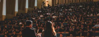 Conférence avec deux intervenants s’exprimant devant un large public dans un amphithéâtre.