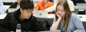 Étudiants travaillant ensemble sur un ordinateur portable dans une salle de classe moderne durant une session académique.