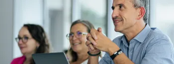 Participants de l’Executive MBA à emlyon écoutant attentivement pendant un cours de business, avec des ordinateurs portables visibles sur les tables de la salle de classe.