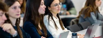 Étudiants assis dans une salle de cours, utilisant des ordinateurs portables lors d’une session de formation universitaire.