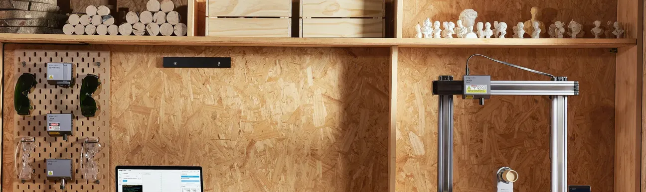 A computer resting on a wooden desk, with various work tools placed on it, and above it, there are wooden shelves holding various objects