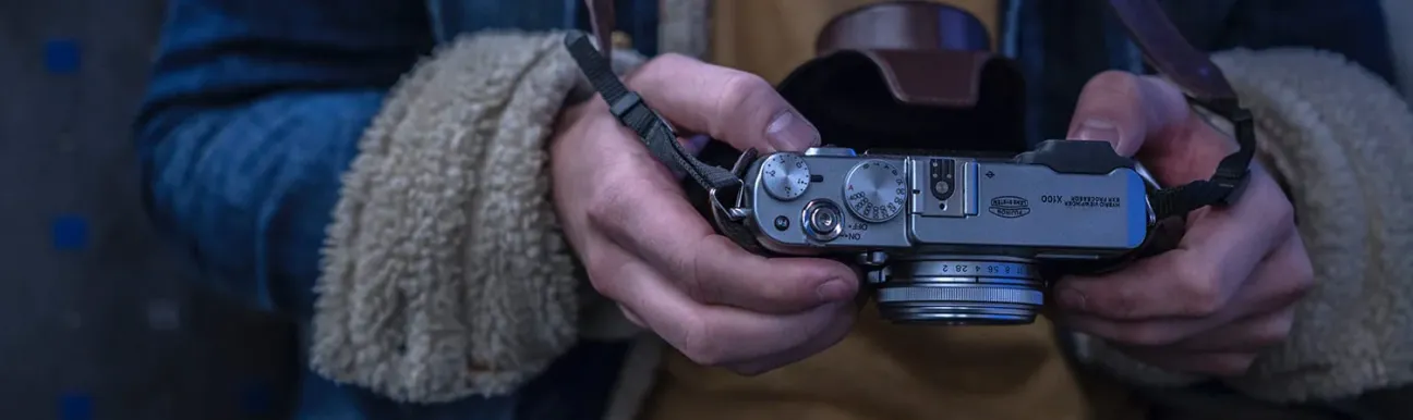 A close-up shot of a person holding a classic camera, showcasing its intricate dials and lens.