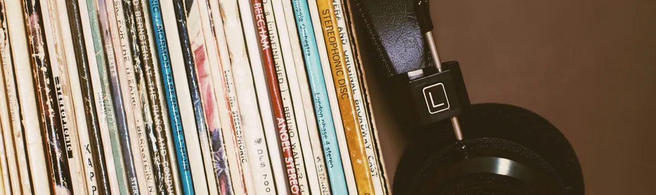 Headphones resting next to a stack of vinyl records
