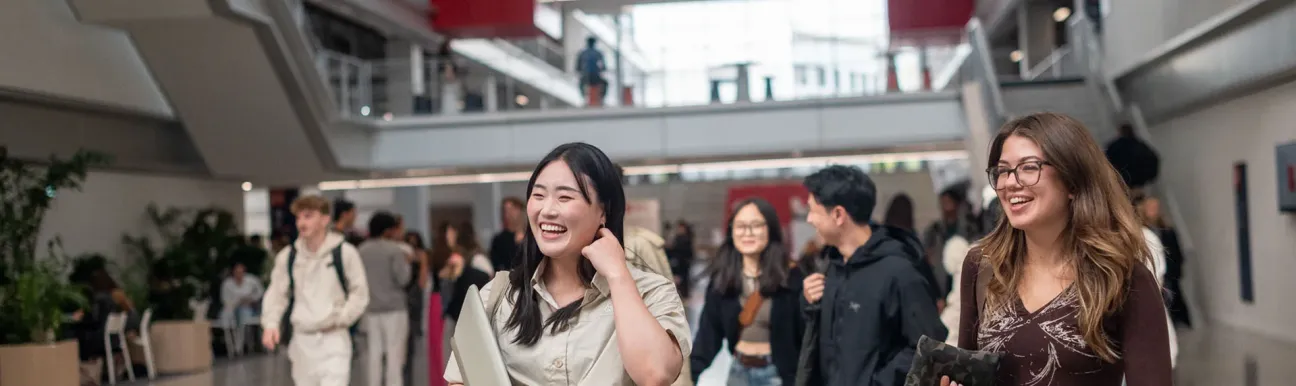 Étudiants dans le hall principal du campus d'emlyon à Lyon, illustrant la vie étudiante, les déplacements quotidiens et l’architecture contemporaine d’une école de management.