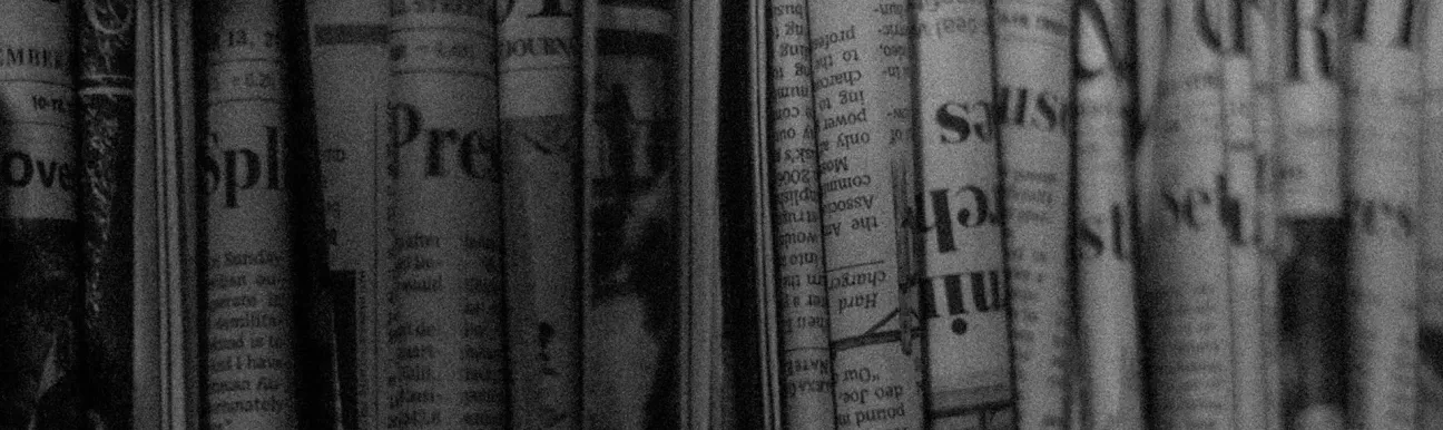 Newspapers and magazines displayed on a shelf for news and information monitoring.