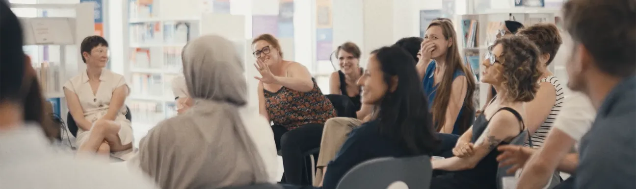Groupe de personnes participant à une discussion dans un espace de bibliothèque ou de centre de ressources. Afficher plus de lignes