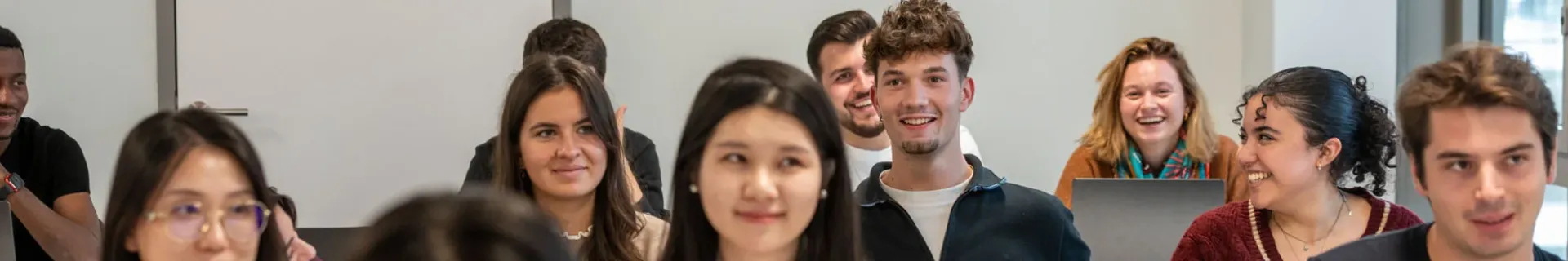 Salle de classe avec des étudiants emlyon assis à des bureaux, utilisant des ordinateurs portables et des tablettes pendant un cours.