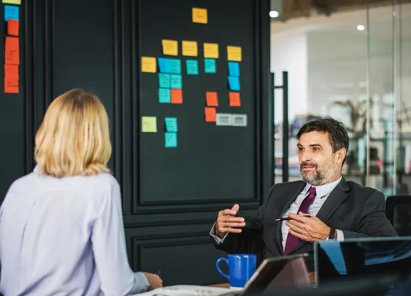 Le dirigeant doit-il donner du sens à ses collaborateurs Un dirigeant et une collaboratrice en tenue professionnelle discutent