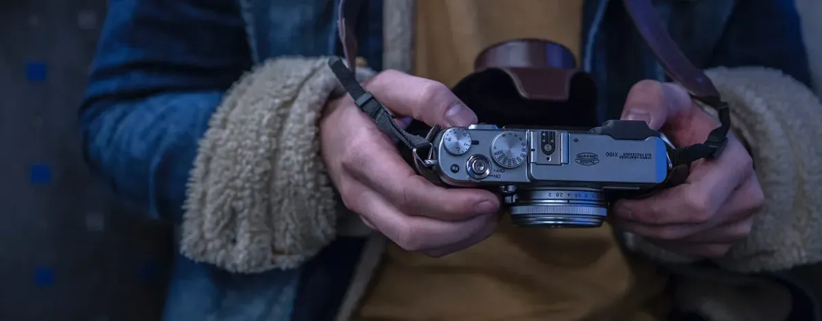A close-up shot of a person holding a classic camera, showcasing its intricate dials and lens.