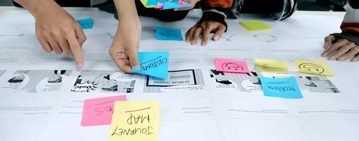 A close-up shot of hands moving post-it notes and papers on a desk.