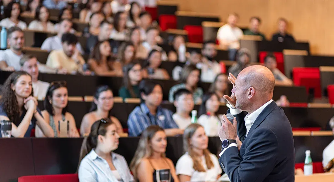Speaker presenting during a conference in the packed auditorium of emlyon business school