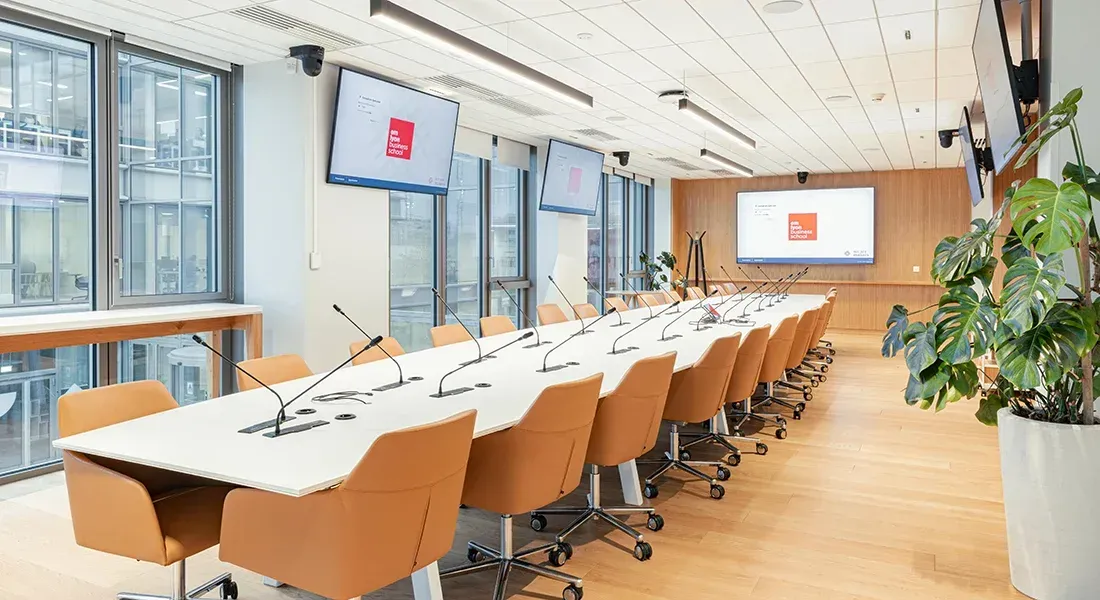 Modern meeting room at emlyon business school with long conference table and integrated screens