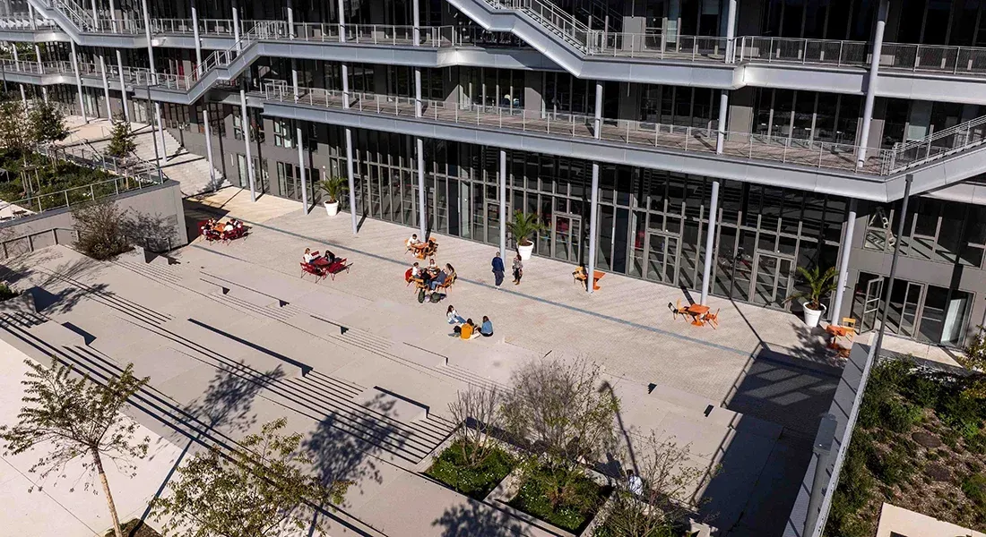 Outdoor terrace and amphitheatre area at emlyon business school with people seated at tables on a sunny day
