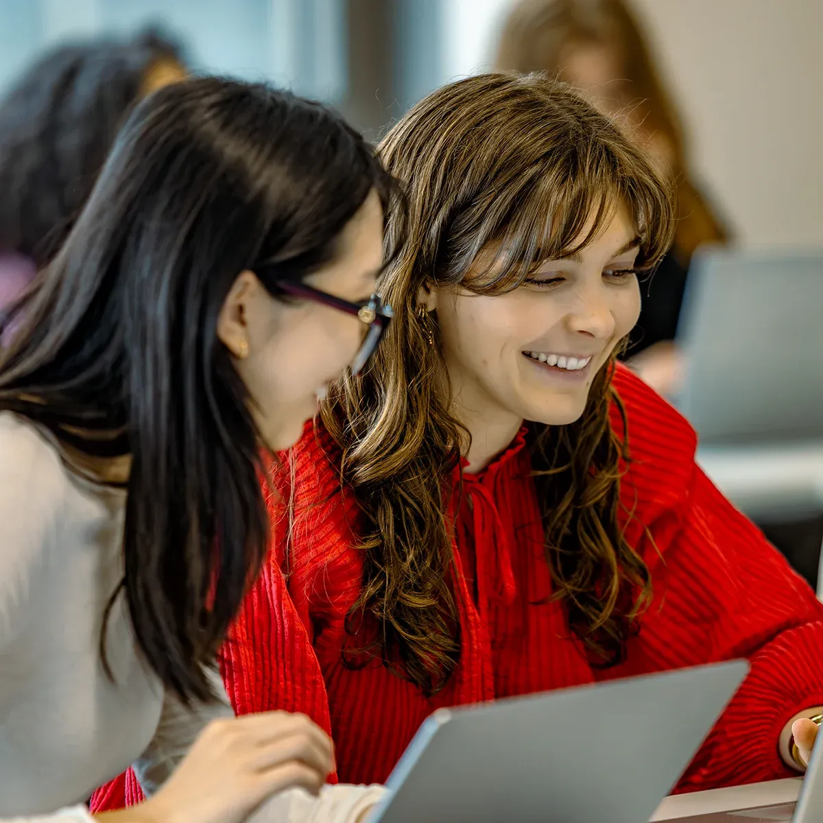 emlyon students working together on a laptop during a collaborative study session in a classroom.