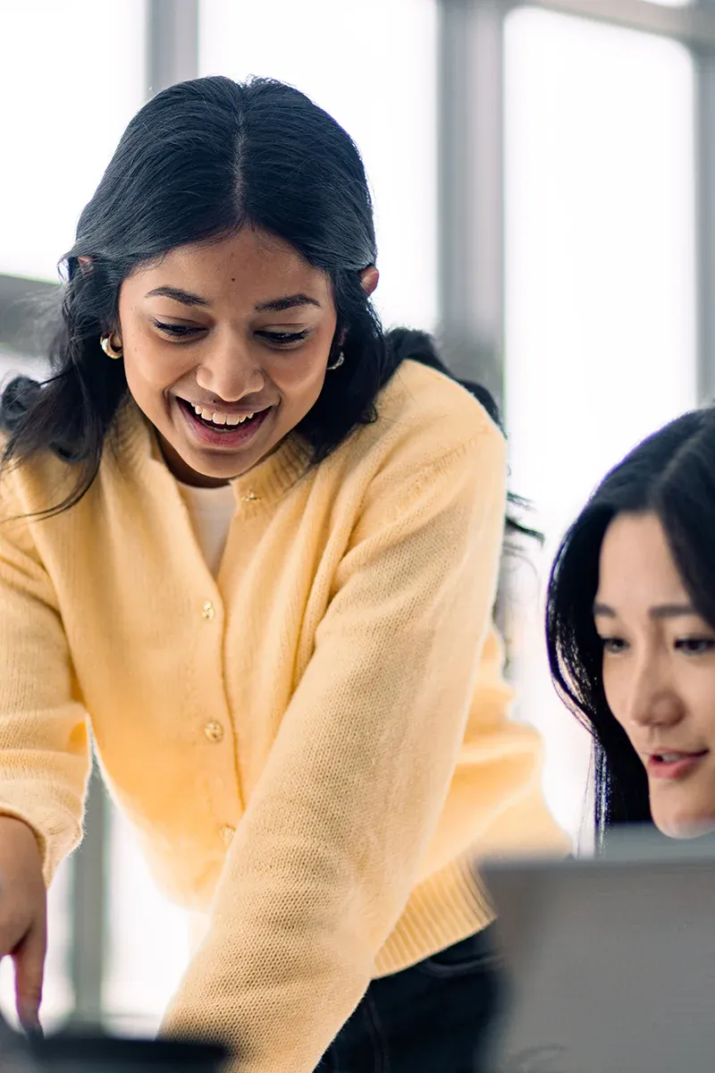 Personnes travaillant ensemble autour d’un ordinateur portable dans un environnement professionnel lumineux, illustrant la collaboration et le recrutement.