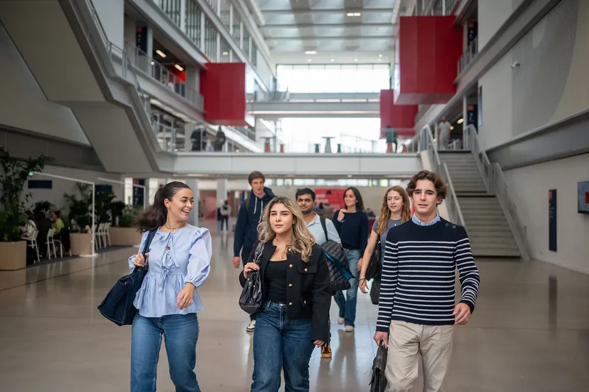 Étudiantes et étudiants marchant dans le hall du campus emlyon business school, espace moderne et lumineux