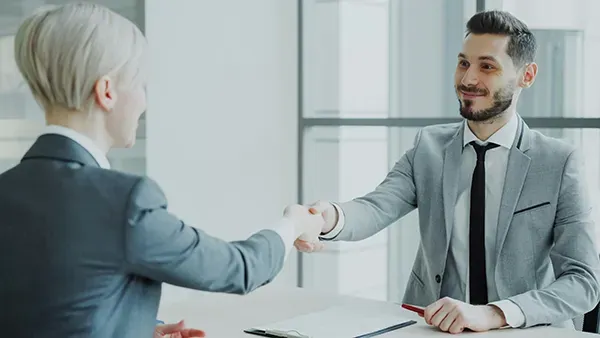  Business professionals shaking hands across a desk during a meeting, symbolizing trust, collaboration, and investor–entrepreneur agreement in a corporate setting.