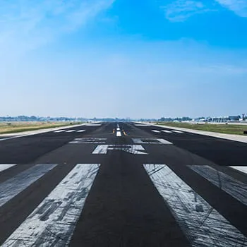 Piste d’aéroport vue de face avec marquages au sol, s’étendant vers l’horizon sous un ciel dégagé.