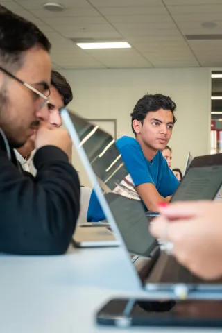 Des étudiants dans une salle de cours, échangeant entre eux.