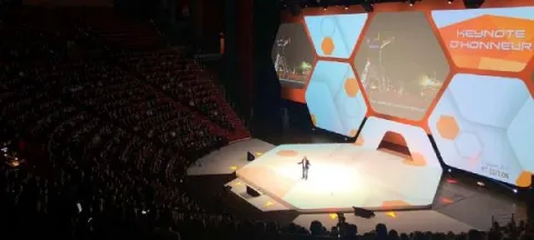 Scène spacieuse dotée d'un grand écran, avec des spectateurs, témoignant d'un événement captivant.