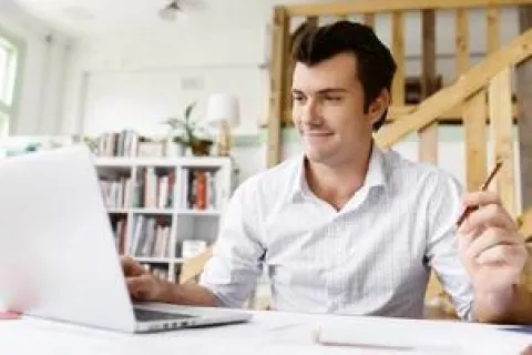 Un homme assis à une table, travaillant sur un ordinateur portable.