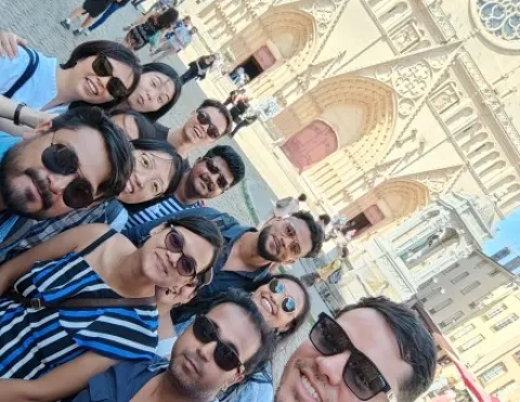 Un groupe de personnes prenant un selfie devant une cathédrale majestueuse, capturant un moment de joie collective.