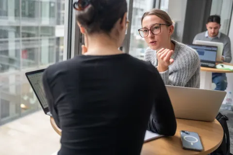 Deux femmes en train de discuter devant leurs ordinateurs