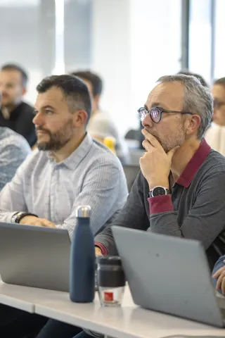 Participants de l’executive education d’emlyon assistant à une session de formation professionnelle, travaillant sur ordinateurs portables dans une salle de cours moderne