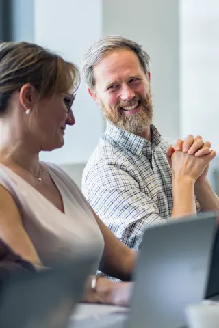 Participants of an emlyon executive program engaging in discussion during a training session, seated at laptops in a modern classroom