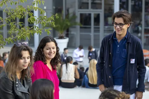 emlyon business school students gathered outside on the Lyon campus forecourt in front of the main entrance.