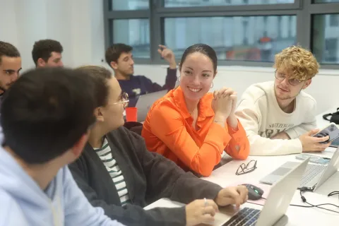 Étudiants en discussion autour d’une table lors d’un travail de groupe dans une salle de cours.