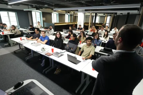 Group work session from the emlyon business school MSc program with students collaborating around a laptop.