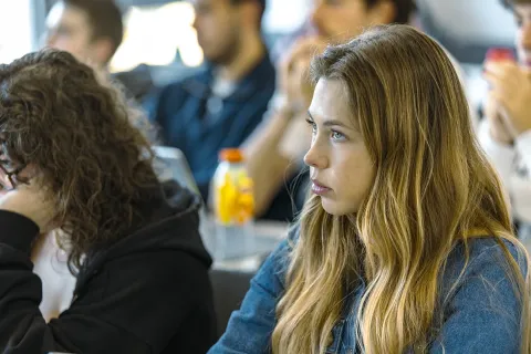 Students attending a classroom session, taking notes and following a presentation.