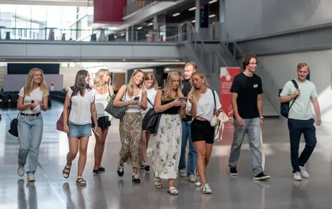 Plusieurs étudiants traversent le hall principal du campus d'emlyon de Lyon, un espace lumineux et moderne reflétant l’environnement d’apprentissage innovant de l’école