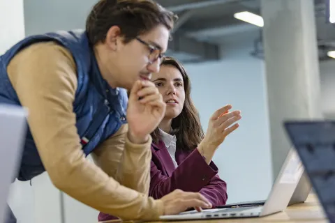 Étudiants travaillant ensemble autour d’un ordinateur portable dans un espace de travail du campus.
