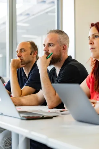 E2MG program participants at emlyon business school listening to a lecture and taking notes on laptops during a training session.