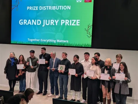 Presentation in the emlyon lecture hall with a seated audience, two speakers on stage, and a screen displaying “Grand jury prize”.